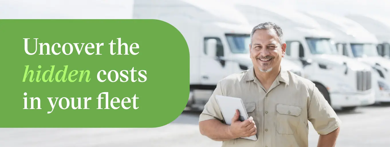Fleet manager reviewing cost-per-mile data on a tablet near semi trucks